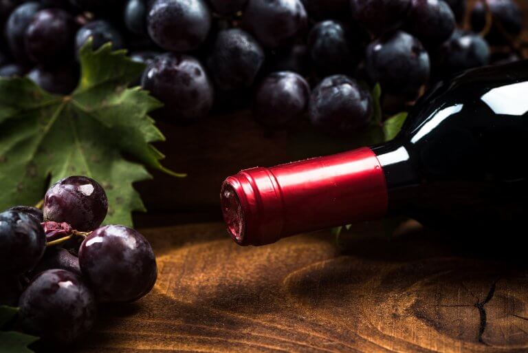 Bottle of red wine and fresh vine grapes